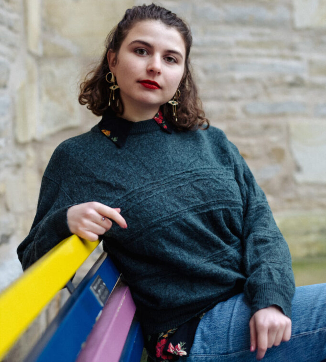 Porträt-Foto der Autorin Özge Inan, auf einer farbigen Bank sitzend.